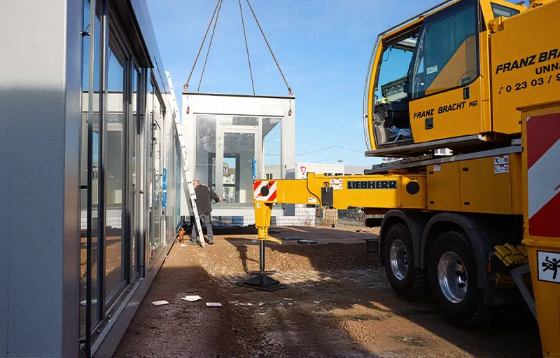Ein vorgefertigtes Raummodul wird per Kran auf der Baustelle in Iserlohn positioniert